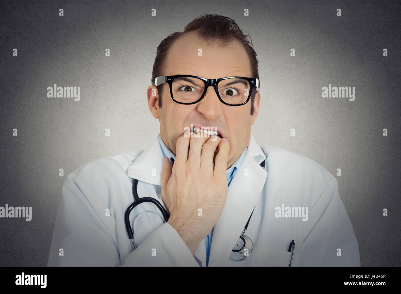 Closeup portrait young insecure, crazy male doctor uncertain psychiatrist with glasses looking funny, scared, craving anxious isolated grey background Stock Photo
