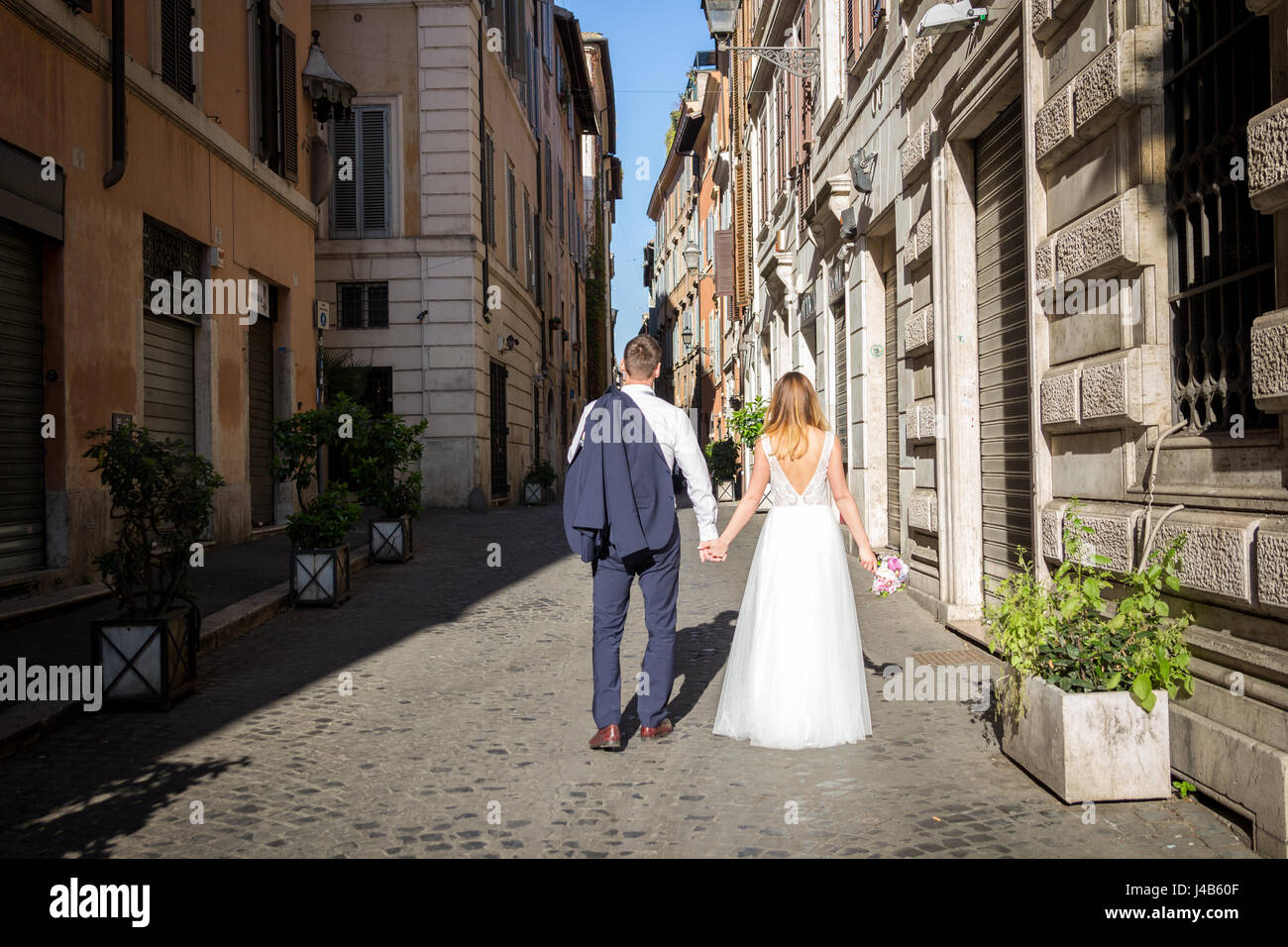 Young beautiful bride and groom on the wedding walk through the streets of old Rome, Italy. Stock Photo