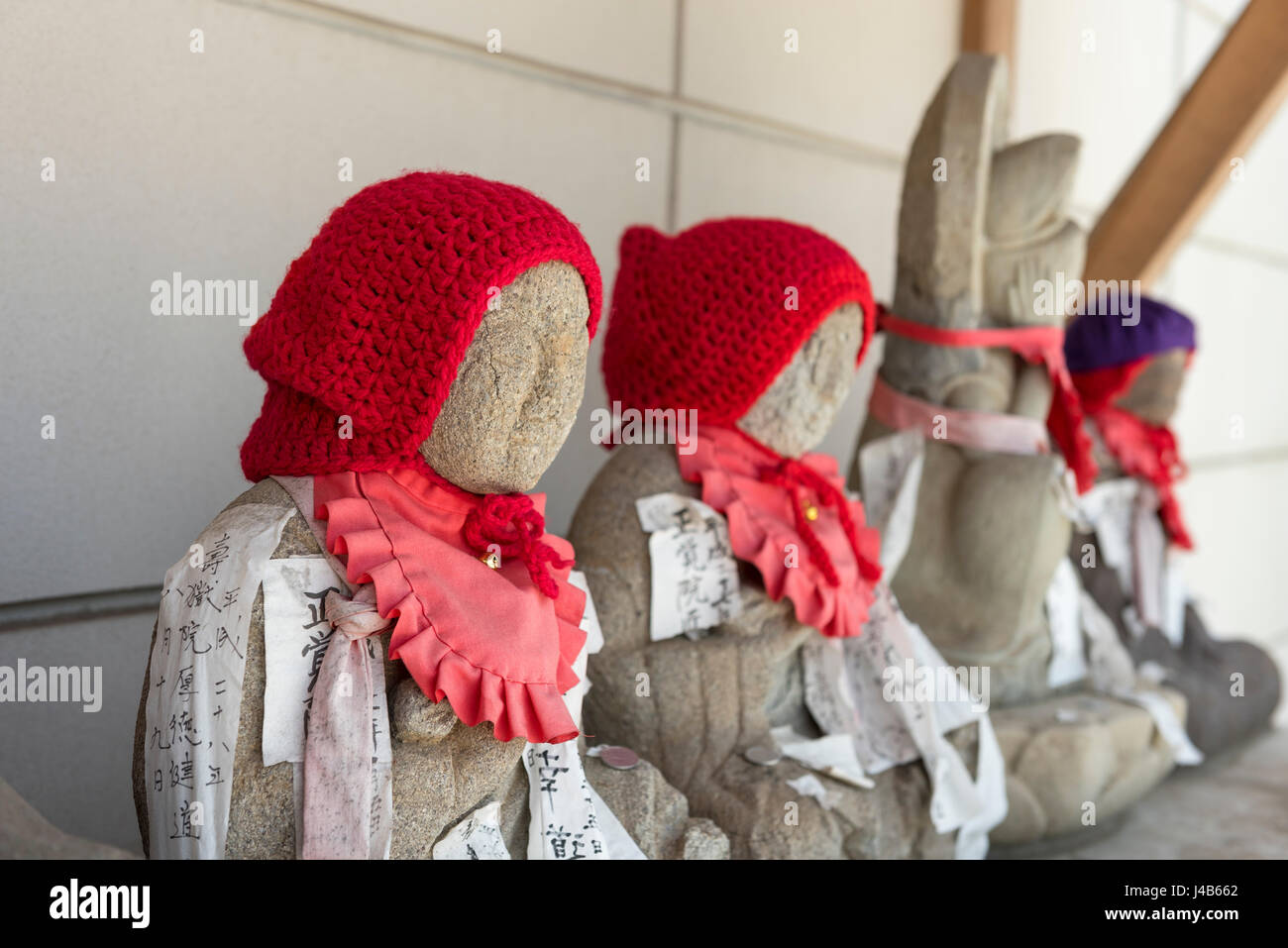Statuettes wearing red woollen hats outside a Buddhist temple in Narita Stock Photo