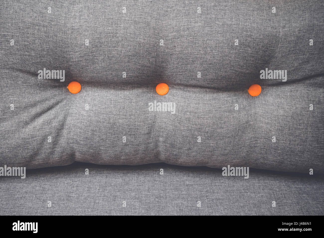 Pillow In Grey Color With Two Round Orange Buttons In A Couch And