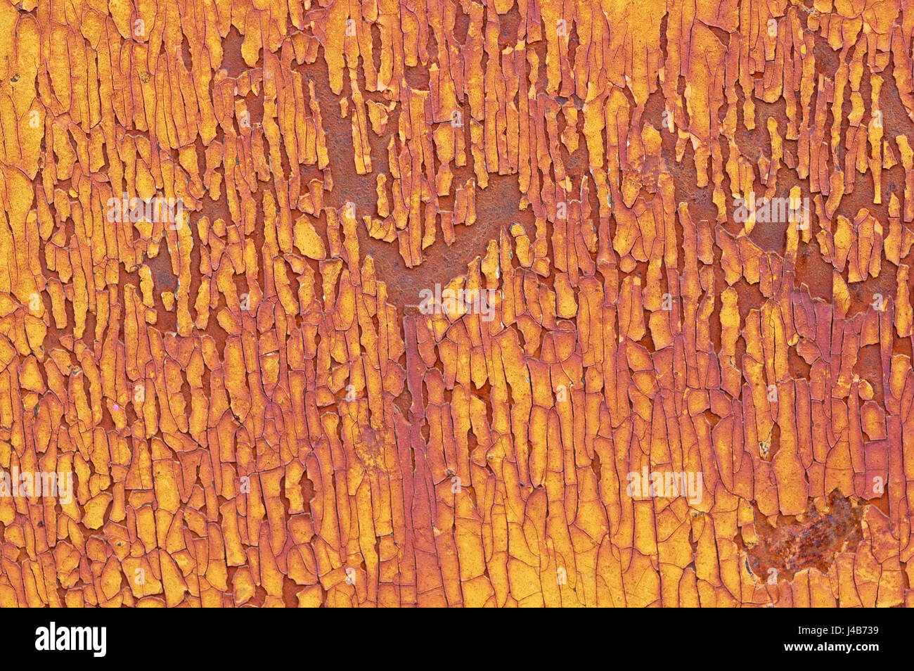 cracked and flaky yellow paint on a rusty metal background Stock Photo