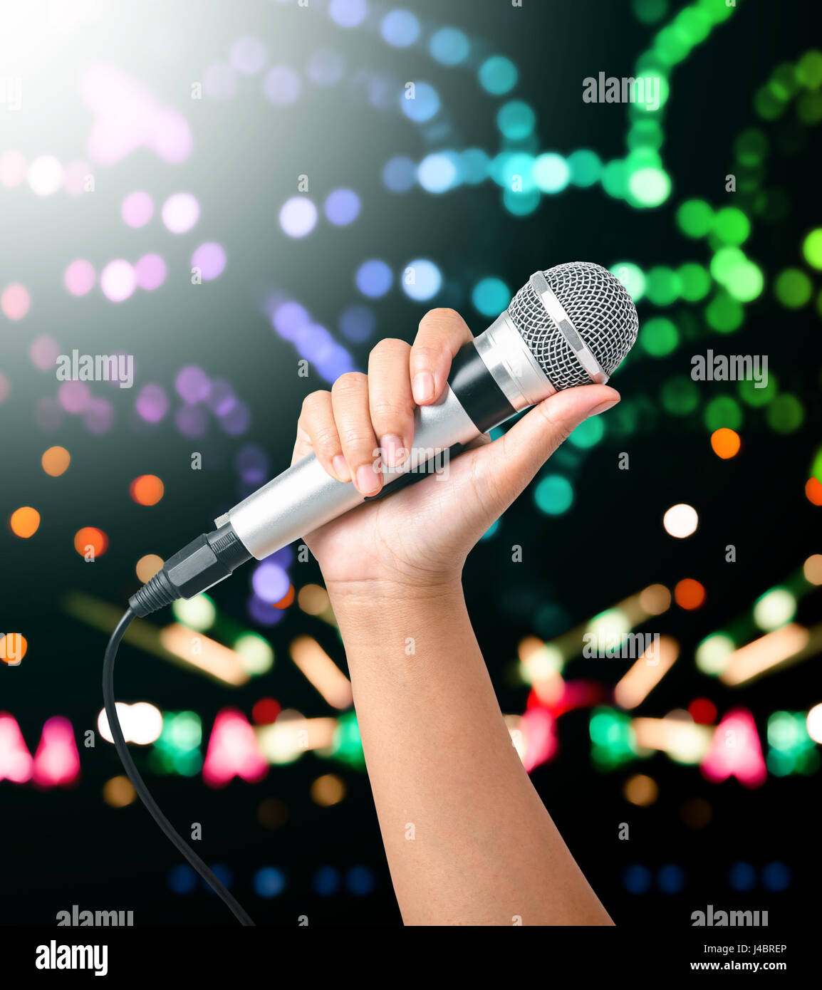 Mircrophone Image Hand holding microphone against colourful on stage background Stock ...