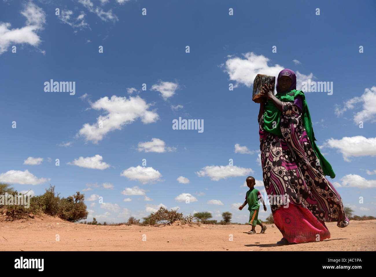 Villagers carry bags of rice, sugar, dates and palm oil back to their houses after collecting their food distribution from charity Action Aid in Sayla Bari, Somaliland. Stock Photo