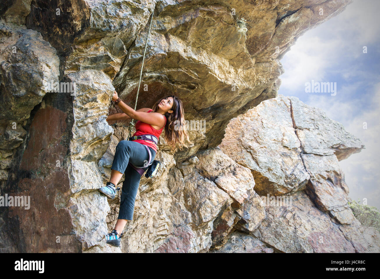 Thirty-year-old female top ropes boulder problem in Glen Park Canyon, San Francisco. Stock Photo
