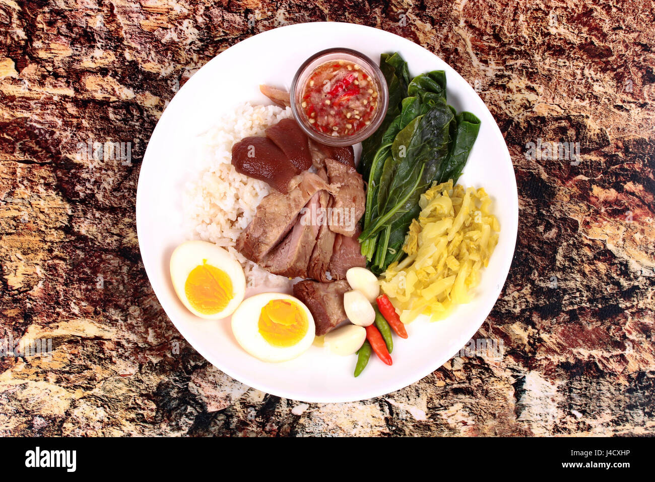 Chinese Thai food,Jasmine rice with stewed pork hock topped boiled eggs,boiled kale,chili,big garlic and pickled turnip with spicy sour sauce.Call Kha Stock Photo