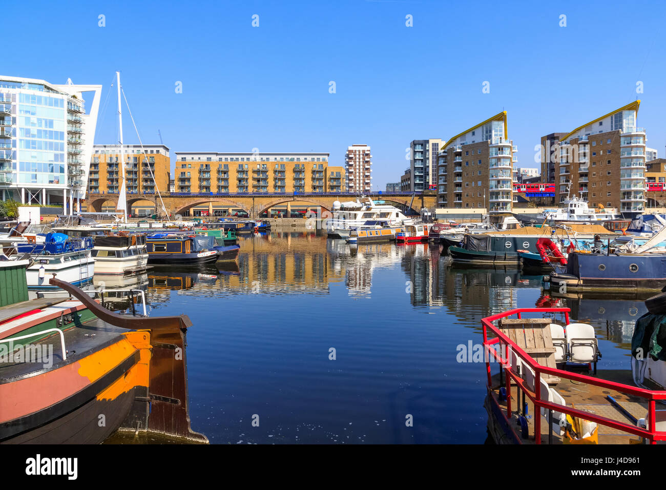 Boats moored at Limehouse Basin Marina in London with DLR passing in the background Stock Photo