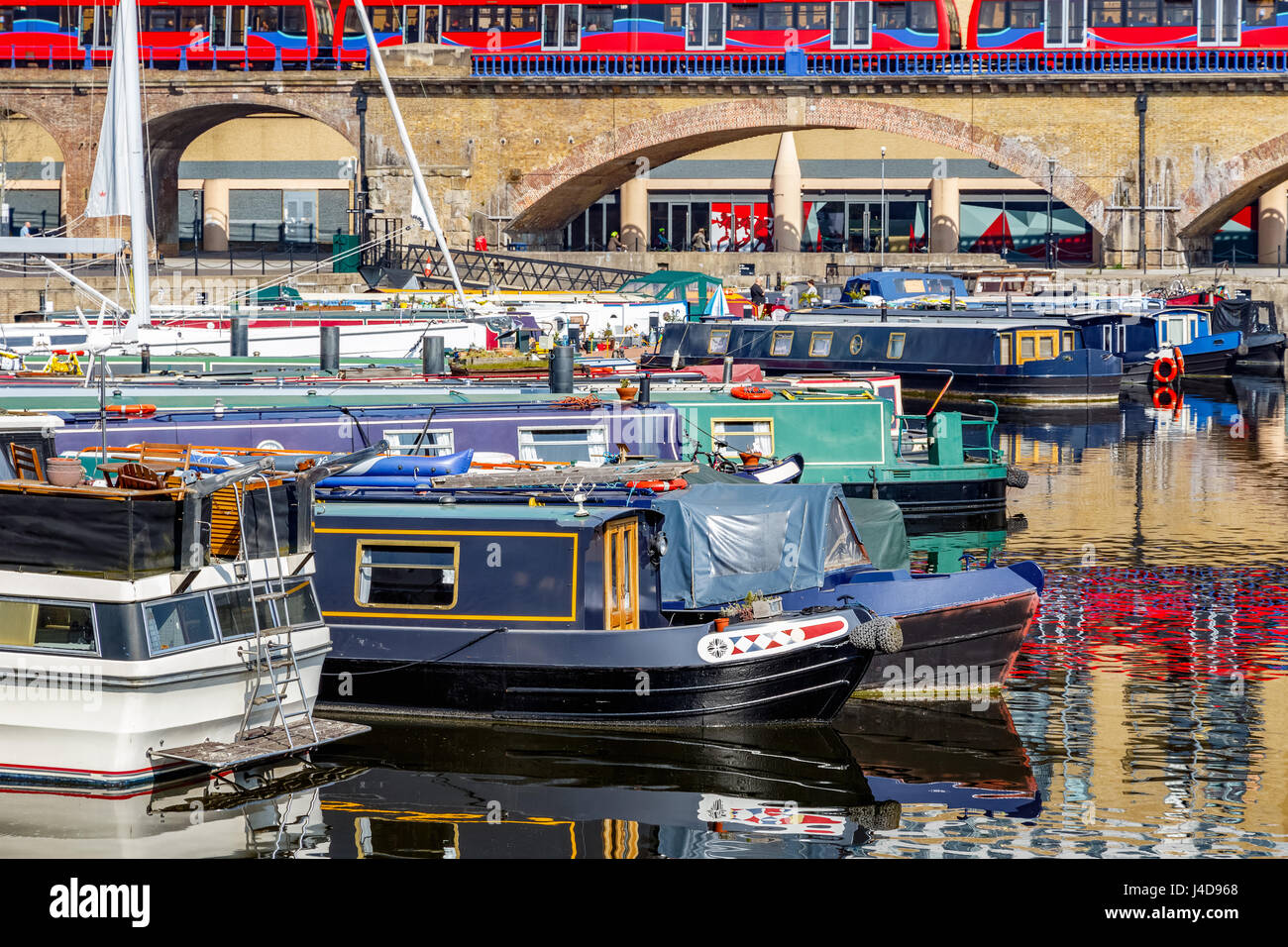 Boats moored at Limehouse Basin Marina in London with DLR passing in the background Stock Photo