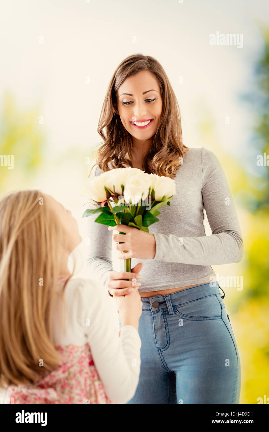 Cute daughter giving her mother bouquet white roses for Mother's Day