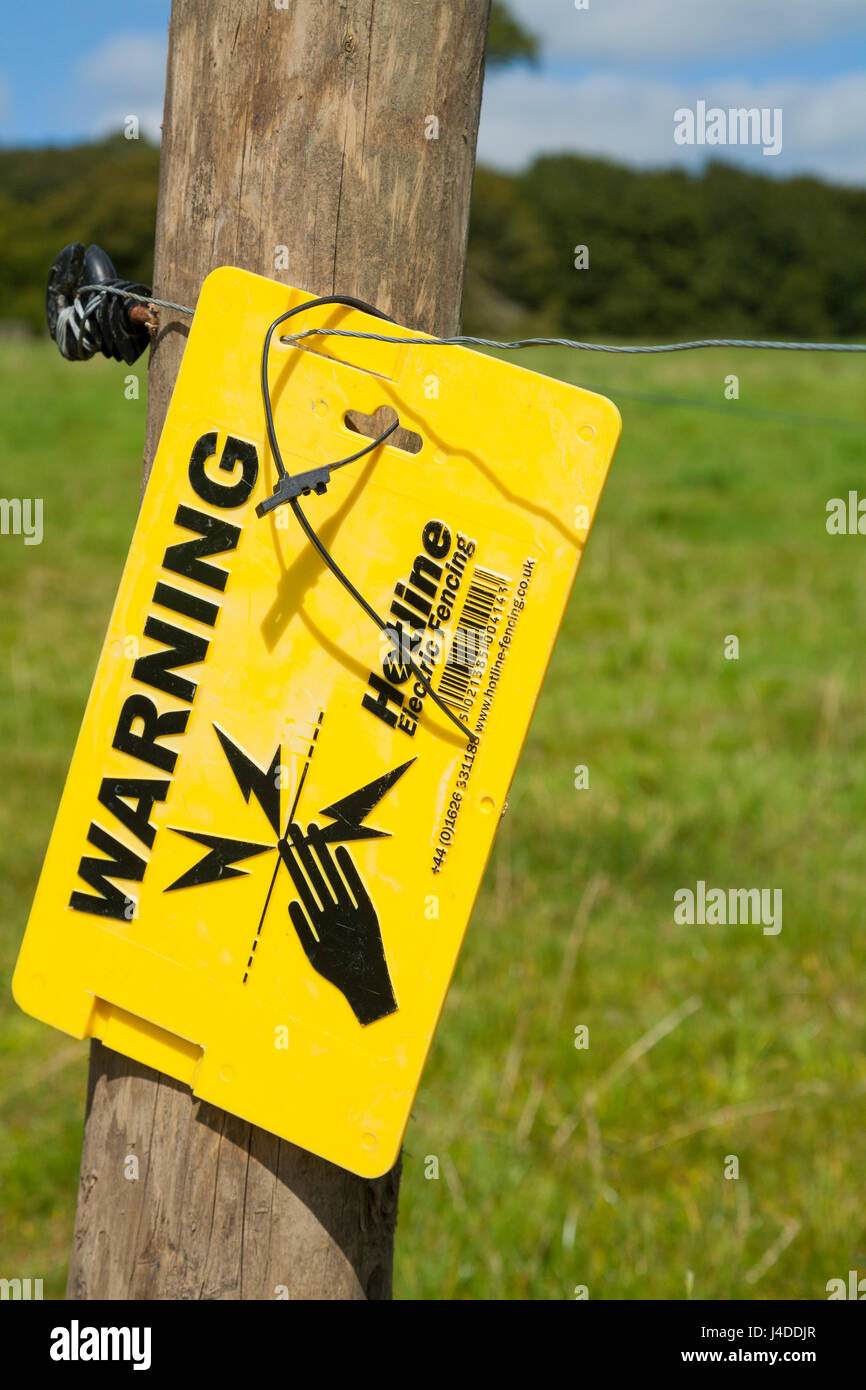 Warning sign to warn pedestrians of electrified fence / electric fences to prevent grazing animals from wandering and protect field / fields / agricultural land from pedestrians & intruders. UK Stock Photo