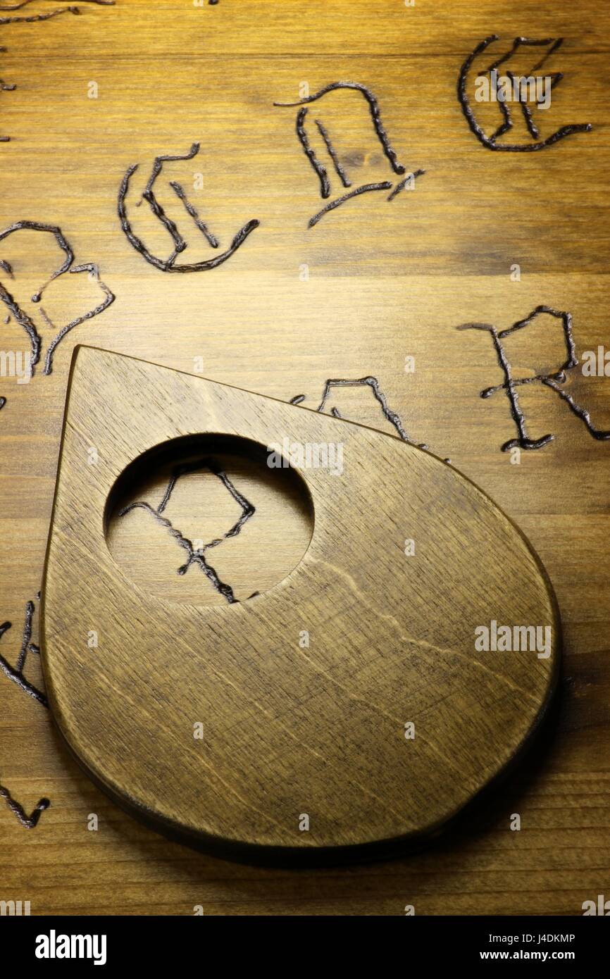 planchette on wooden talking board Stock Photo