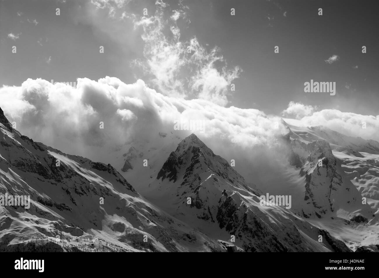 Black and white view on snow sunlight mountains in clouds. Caucasus ...