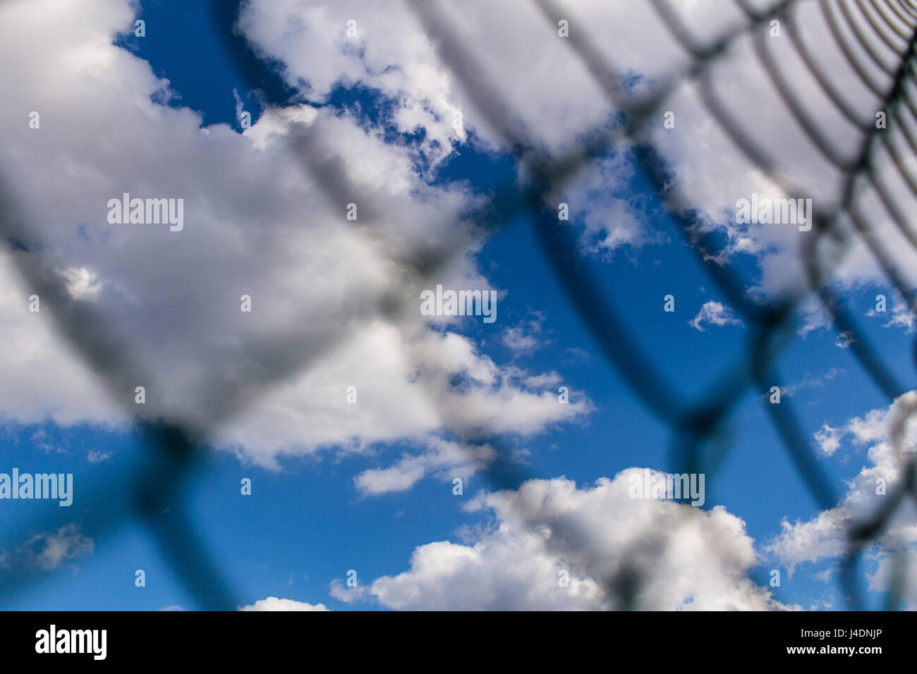 Background of Metal mesh fence against deep blue sky with white fluffy ...