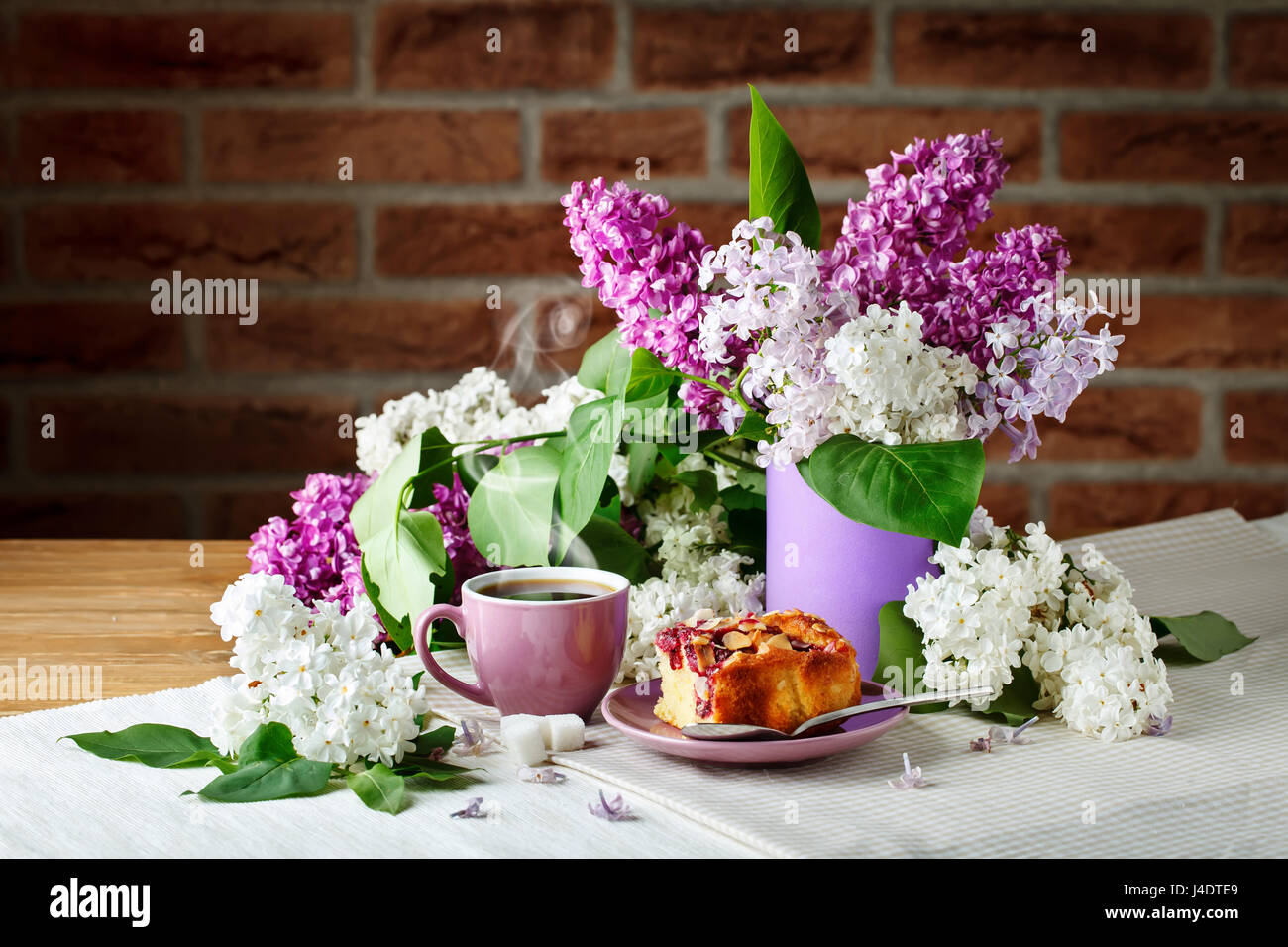 Still life with branches of lilac and a Cup of coffee and cake on a ...