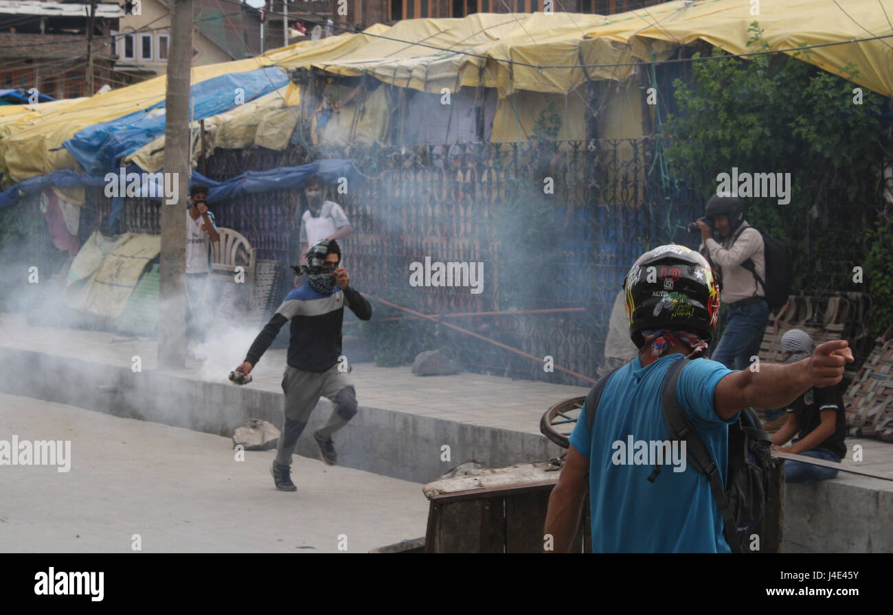 Srinagar, Kashmir. 12th May, 2017. .A Kashmiri protester throws back exploded tear gas shell. Clashes broke out between protesters and security forces in downtown Nowhatta area of Srinagar. Groups of youth indulged in sloganeering and stone- pelting at Indian security forces soon after Friday congregational prayers. According to the report, 102 unarmed civilians were killed in 135 days of unrest that was sparked by the killing on July 8 of Hizbul Mujahideen commander Burhan Wani by the armed forces. Credit: sofi suhail/Alamy Live News Stock Photo