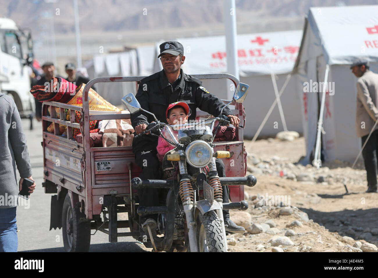 Taxkorgan, China's Xinjiang Uygur Autonomous Region. 12th May, 2017. A staff worker helps villagers to transfer personal belongings at an emergency shelter in Quzgun Village of quake-hit Taxkorgan County, northwest China's Xinjiang Uygur Autonomous Region, May 12, 2017. Eight people have been confirmed dead and 29 others were injured after a 5.5-magnitude earthquake jolted Taxkorgan County till 2:00 p.m. Thursday. China has activated emergency response procedures following the earthquake. Credit: Li Jing/Xinhua/Alamy Live News Stock Photo