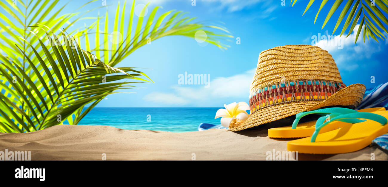 Straw hat and flip flops on beach Stock Photo