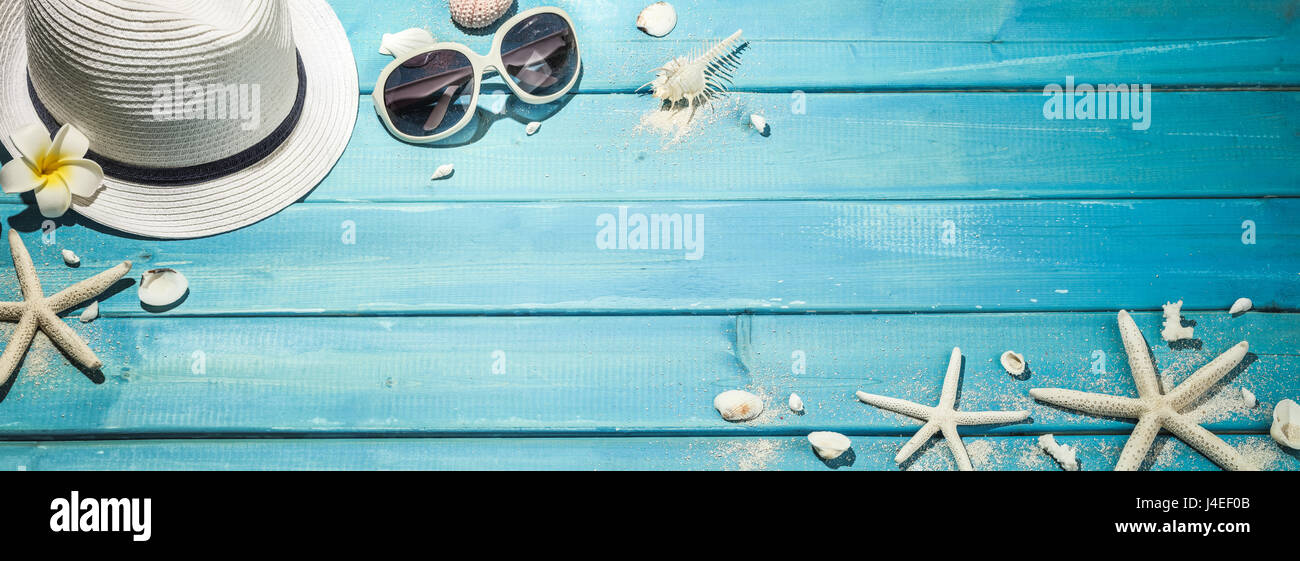 Straw hat, sun glasses and seashells on blue wooden background Stock Photo