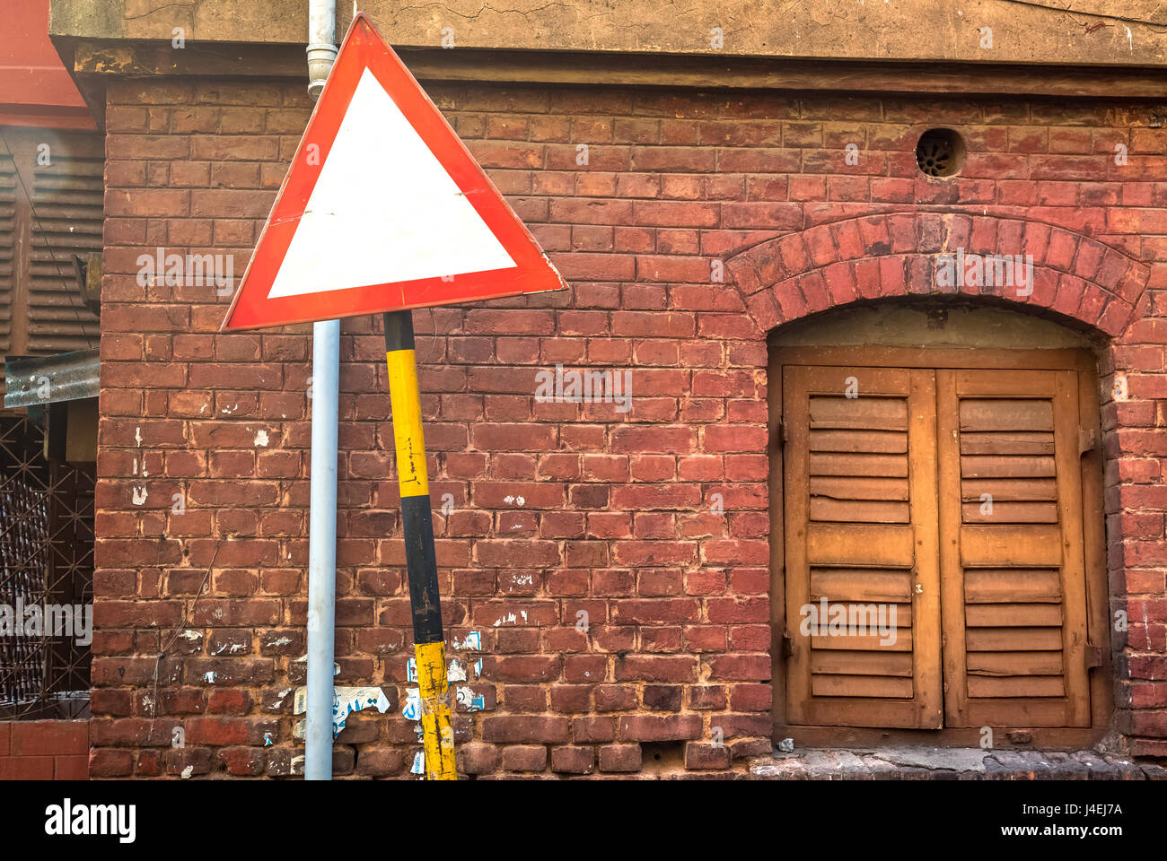 Empty Street sign in front of an ancient red brick wall with closed wooden window. Stock Photo
