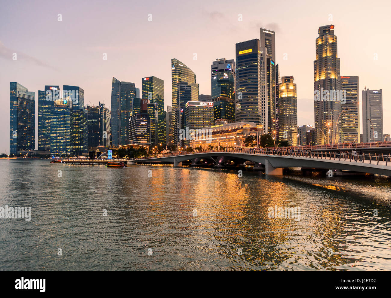 Singapore city sunset over the Jubilee Bridge across to Merlion Park overlooked by the skyscrapers of the downtown CBD and Marina Bay, Singapore Stock Photo