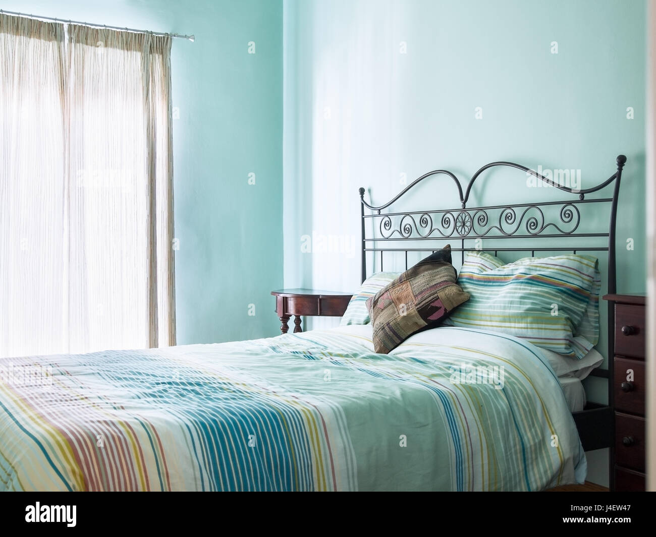 Bright and airy bedroom with rustic furniture and green / turquoise paint and soft furnishings from a bed and breakfast. Stock Photo