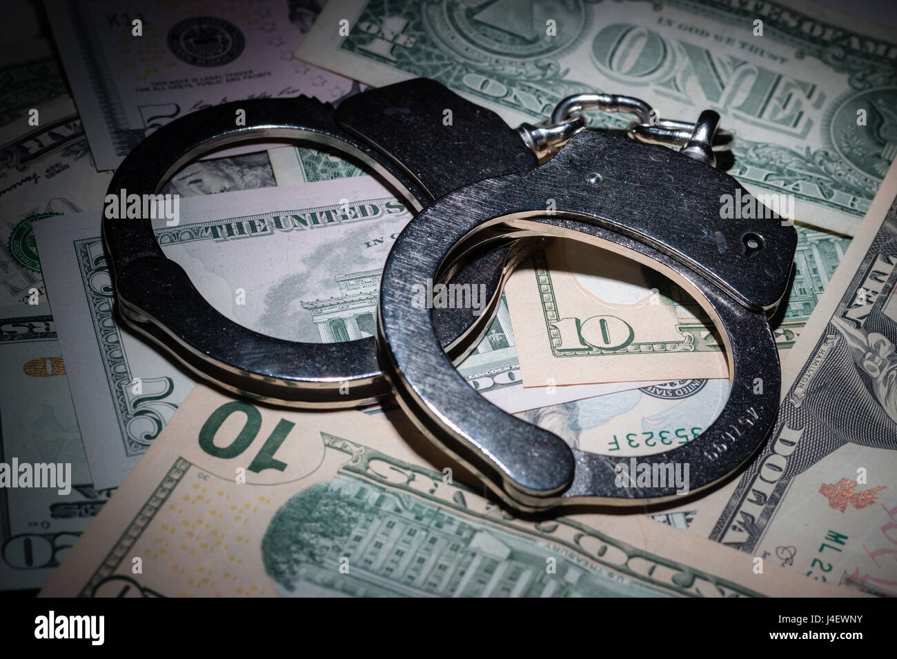 A pair of handcuffs on a pile of American banknotes Stock Photo