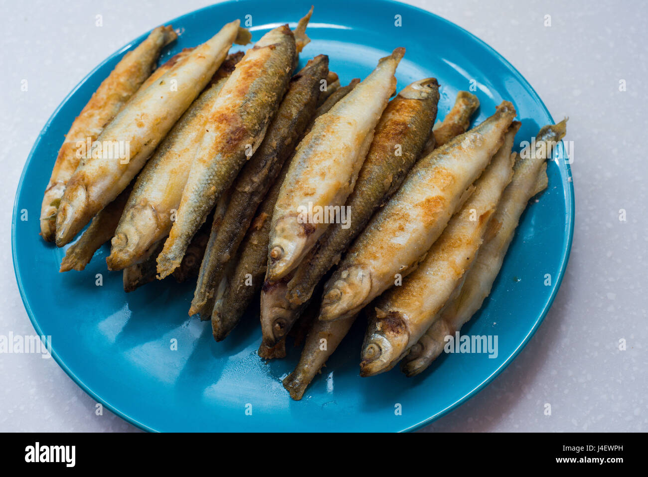 Fried smelts fish lays on a white plate over gray tablecloth Stock Photo