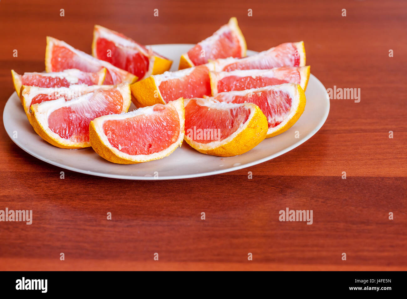 Two grapefruits sliced on lobes on plate Stock Photo Alamy