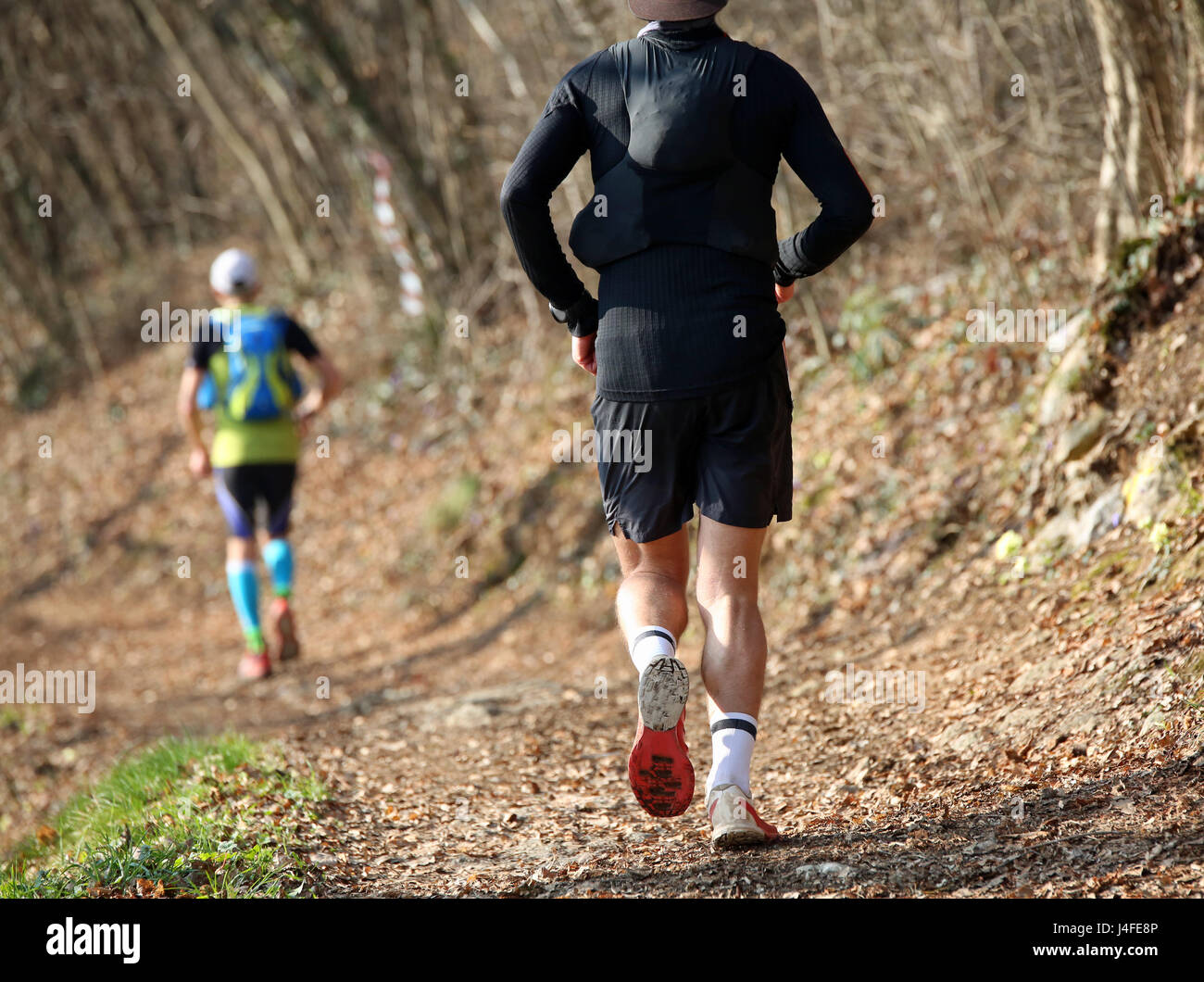 Two runners from behind run along the mountain trail during the racing