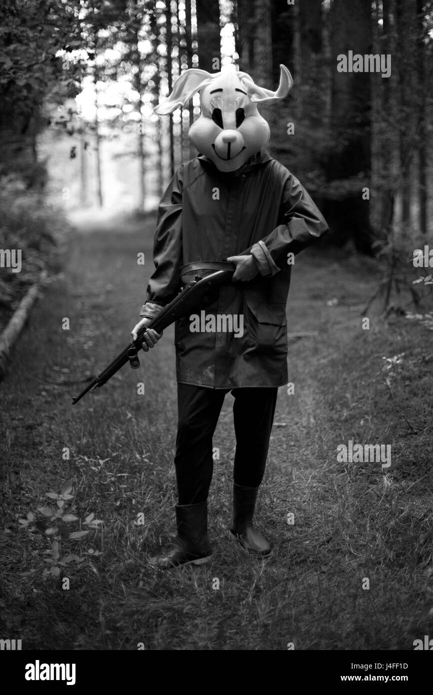 black and white photography. woman hunter wearing a rabbit mask hunting
