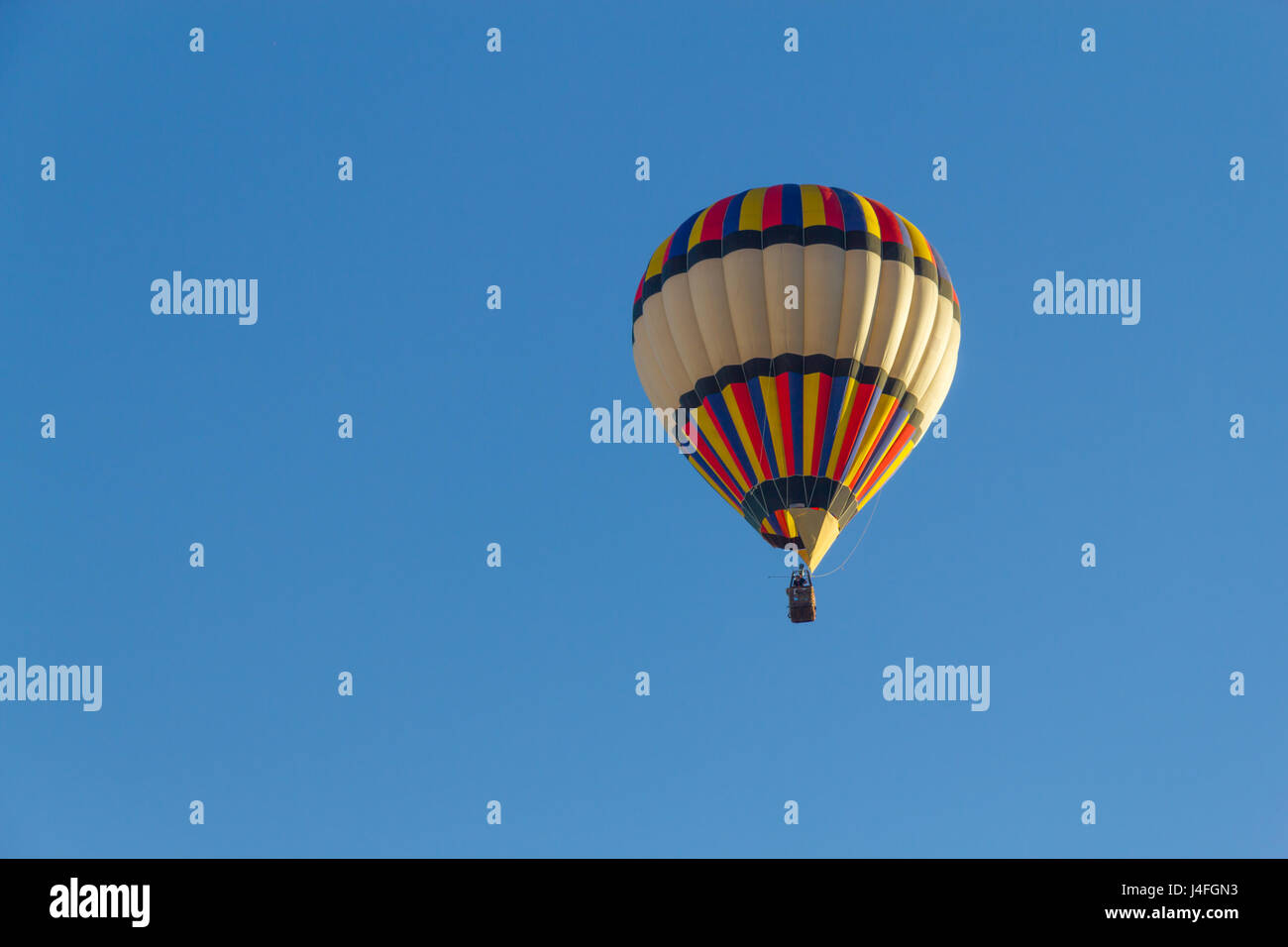Colored hot air balloon flying in a blue sky Stock Photo - Alamy