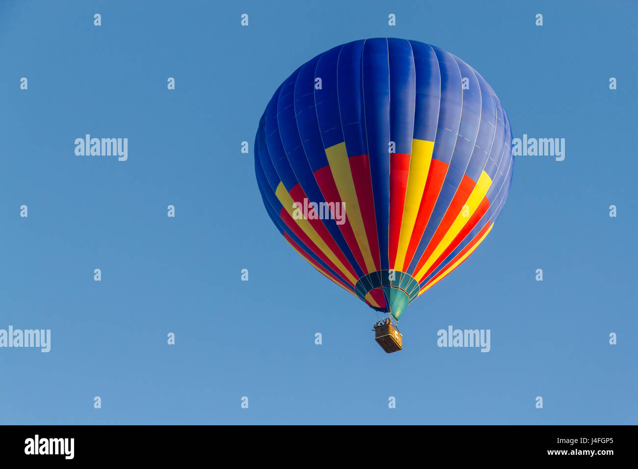 Colored hot air balloon flying in a blue sky Stock Photo - Alamy