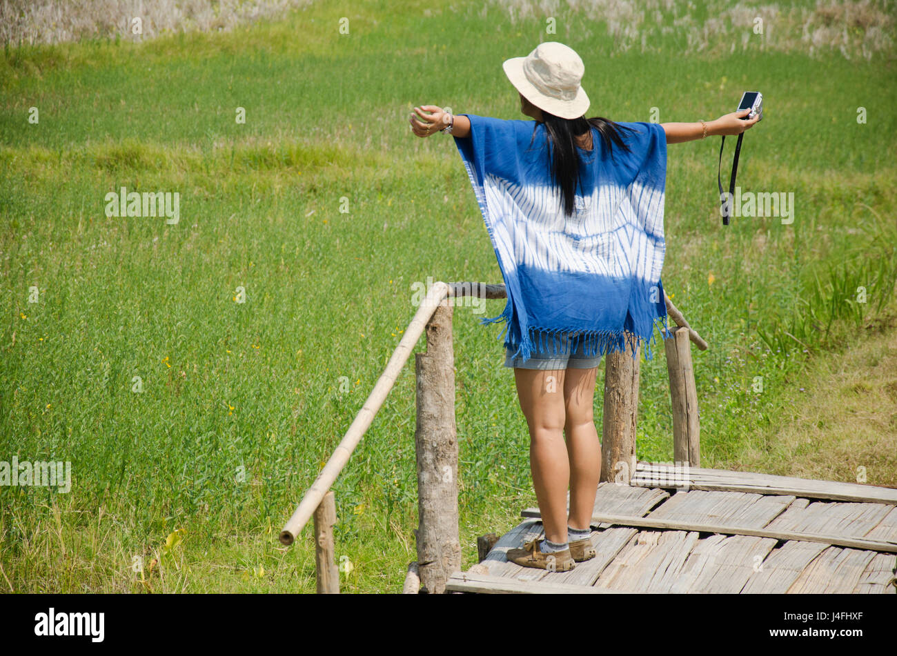 Thai women people travel and posing shooting photo for writing blog on wooden bridge with landscape rice field mountain at Tai Dam ethnic museum house Stock Photo