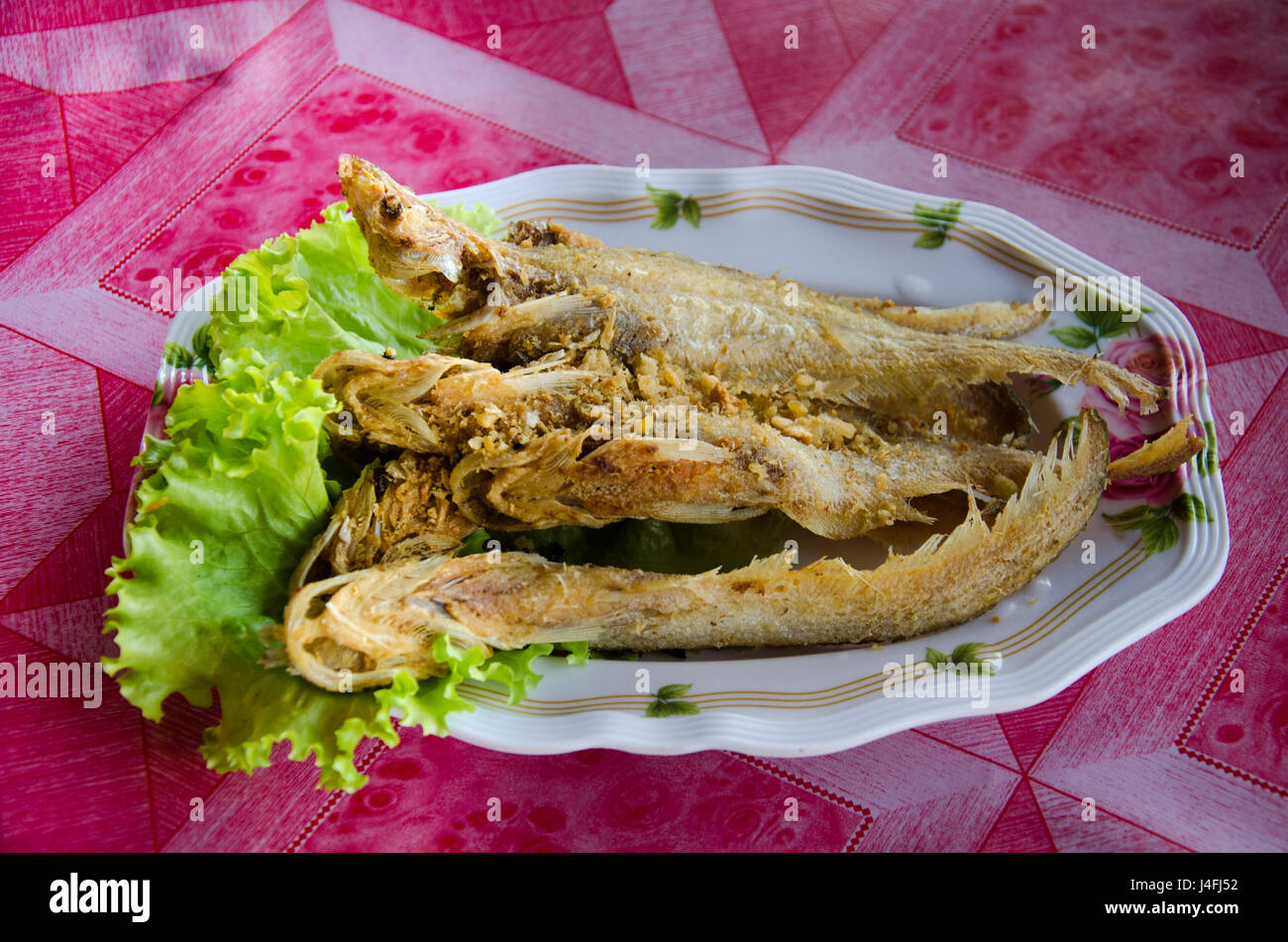Fried Sheatfishes or Siluridae fresh river fish with garlic and pepper severe with vegetable in local restuarant of thailand Stock Photo