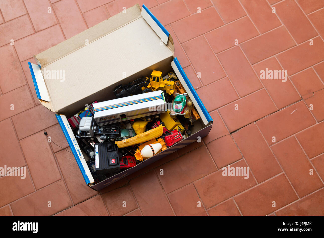 A box of old toys on red tile floor Stock Photo