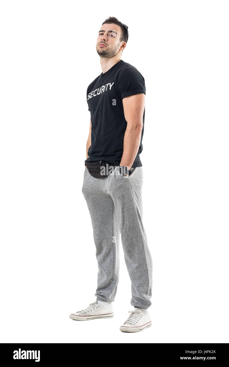 Side view of young macho bouncer with hands in pocket and head tilted back. Full body length portrait isolated on white studio background. Stock Photo