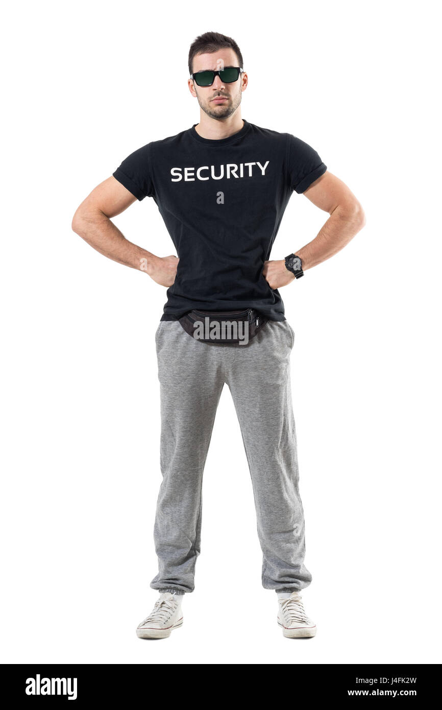 Young strong bouncer in sporty clothes with arms on hips looking at camera. Full body length portrait isolated on white studio background. Stock Photo