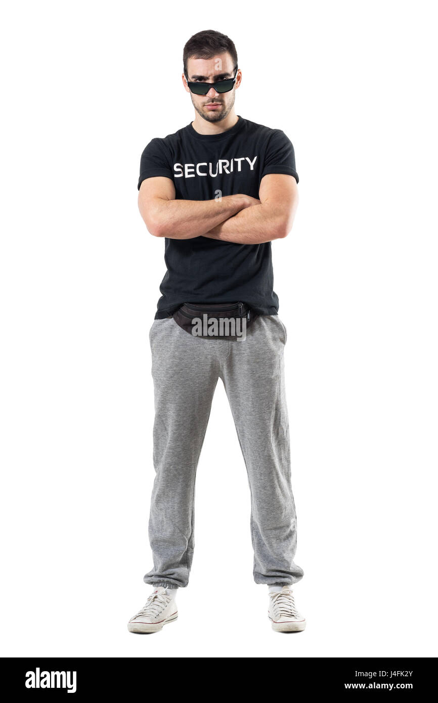 Tough serious bouncer or bodyguard with crossed arms staring at camera. Full body length portrait isolated on white studio background. Stock Photo