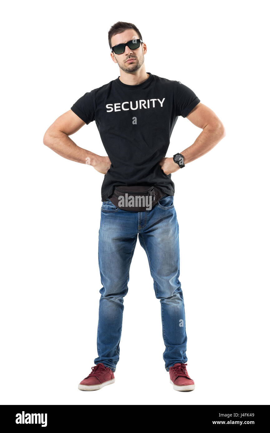 Serious macho bouncer or undercover officer with hands on hips looking at camera. Full body length portrait isolated on white studio background. Stock Photo
