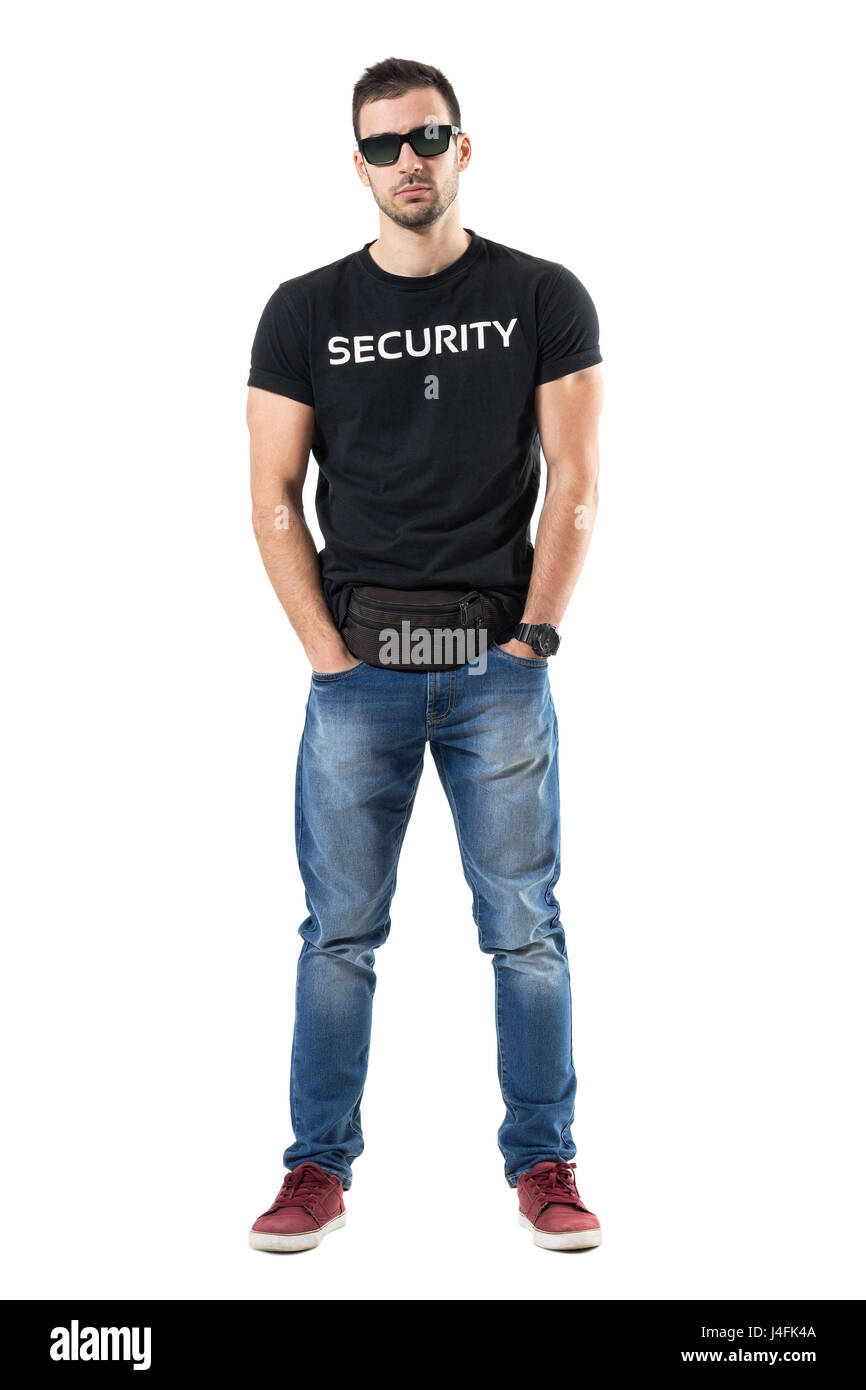Serious undercover cop with hands in pockets wearing waist bag looking at camera. Full body length portrait isolated on white studio background. Stock Photo