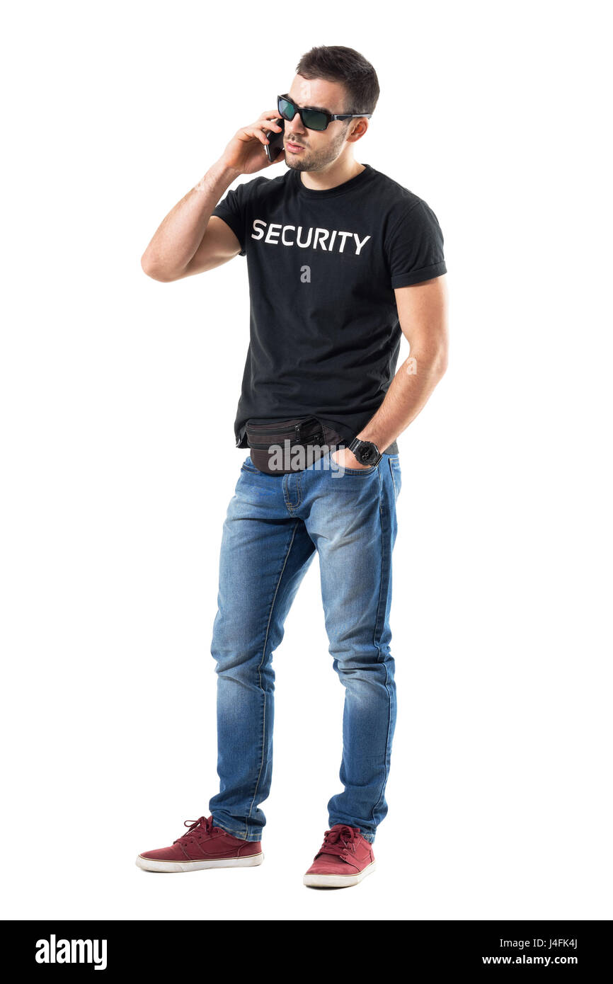 Frustrated young undercover police officer talking on the mobile phone. Full body length portrait isolated on white studio background. Stock Photo