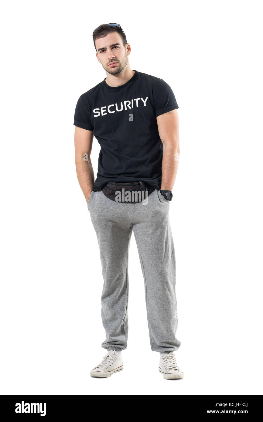 Skeptical young bouncer with hands in pockets frowning and looking at camera. Full body length portrait isolated on white studio background. Stock Photo