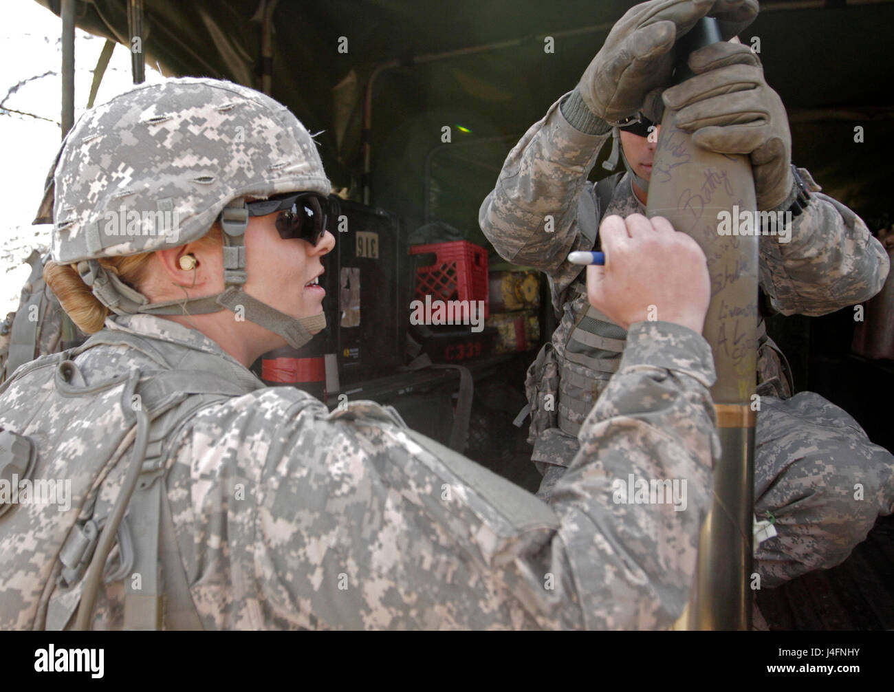 Pfc. Katherine Beatty adds her farewell message to the final shell to be fired from the M119A3 howitzer during the live-fire portion of cannon crewmember advanced individual training. Beatty is the Army’s first 13B cannon crewmember to graduate from advanced individual training, taught in 1st Battalion, 78th Field Artillery. More women are already scheduled to follow Beatty in 13B training, one of the last remaining ground combat military occupational specialties opened to women Jan. 2, 2016. (Army photo by Cindy McIntyre) Stock Photo