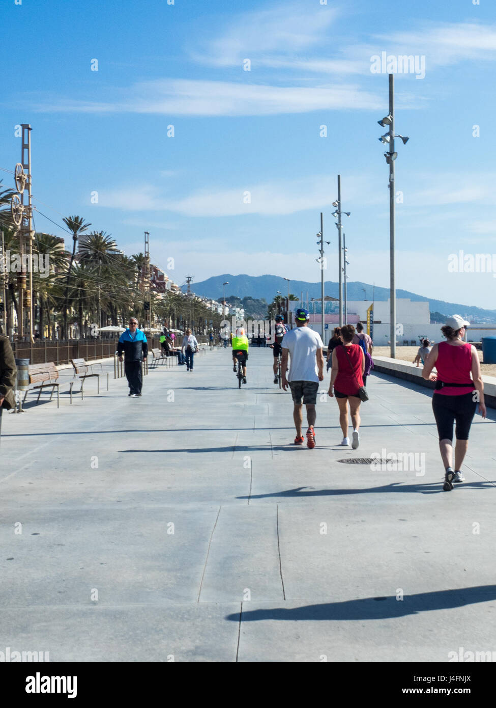 Touring cyclists cycling on the esplanade on the beachfront at Badalona, Spain. Stock Photo