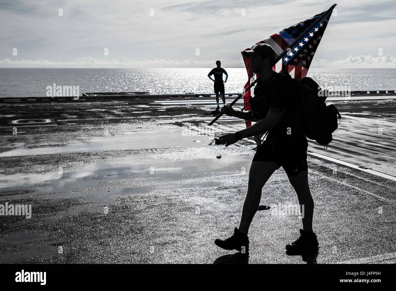 160704-N-NF288-380 SOUTH CHINA SEA (July 4, 2016) Lt. Kris LoveKamp, from St. Louis, carries a 9/11 remembrance flag during a Freedom 5K run on the flight deck of the Navy's only forward-deployed aircraft carrier USS Ronald Reagan (CVN 76) on Independence Day. Ronald Reagan Sailors joined Americans around the world in the celebration of the anniversary of the signing of the Declaration of Independence in 1776. Ronald Reagan, the Carrier Strike Group Five (CSG 5) flagship, is on patrol in the U.S. 7th Fleet area of responsibility supporting security and stability in the Indo-Asia-Pacific region Stock Photo