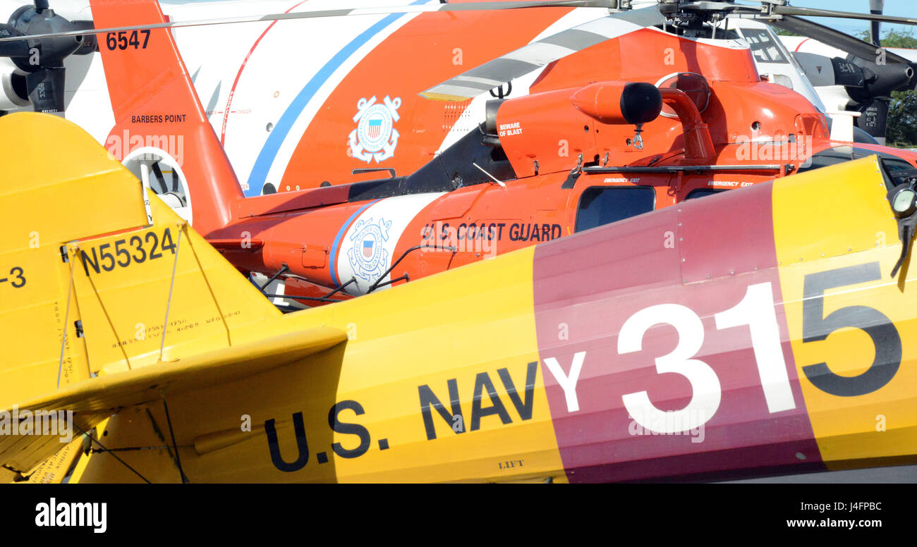 Harry Greene’s Boeing Stearman Kaydet Primary Trainer airplane sits alongside a Coast Guard MH-65 Dolphin helicopter and a Coast Guard HC-130 Hercules airplane on the tarmac at Coast Guard Air Station Barbers Point, Oahu, Jan. 31, 2016. Greene is a helicopter pilot at Air Station Barbers Point and an aircraft enthusiast in his off-duty time. (U.S. Coast Guard photo by Petty Officer 2nd Class Tara Molle/Released) Stock Photo