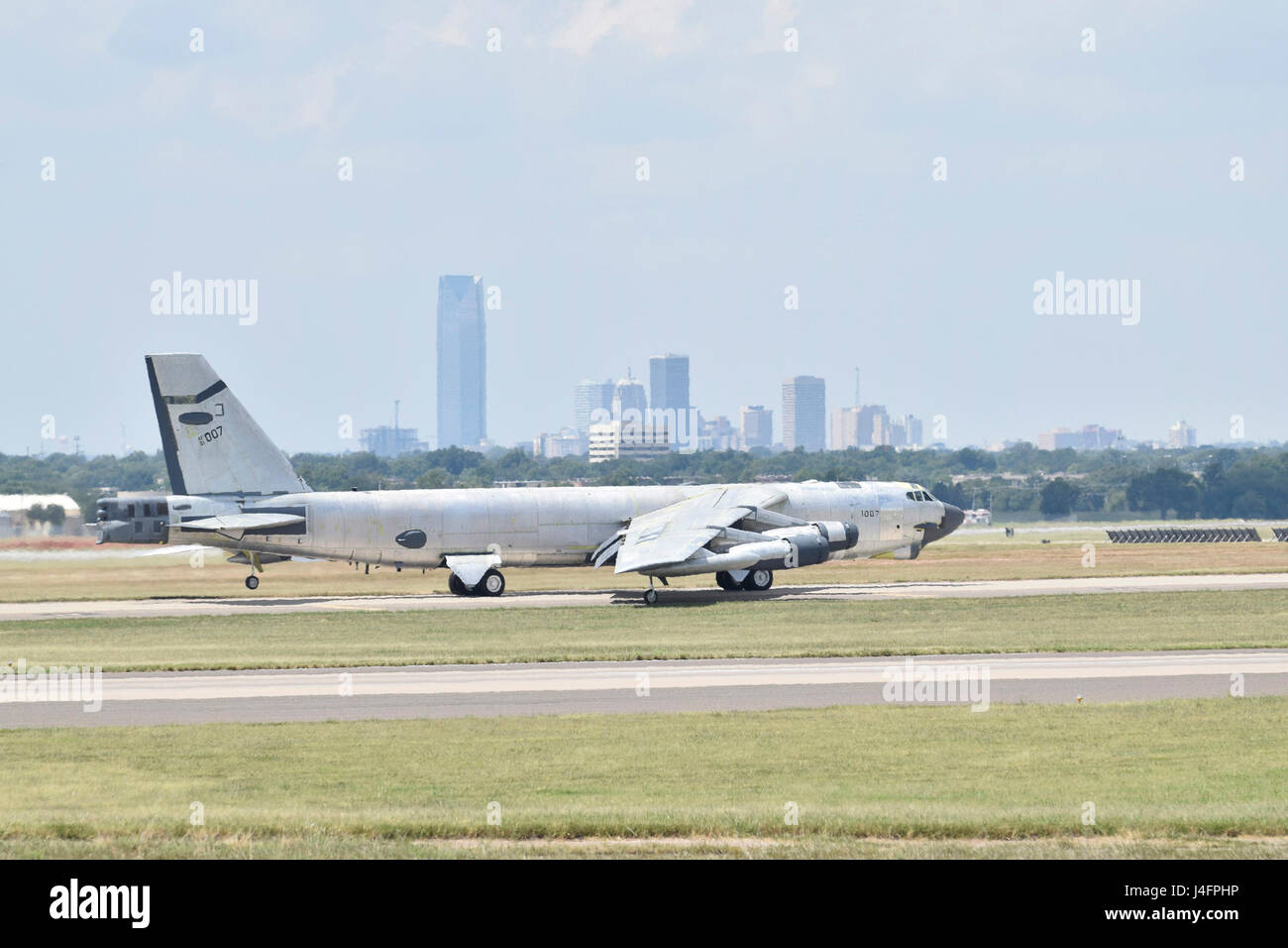 B-52H, 61-0007, 'Ghost Rider,' taxis with the skyline of Oklahoma City visible in the background before an attempted functional test flight after undergoing a 19-month overhaul and upgrade by the Oklahoma City Air Logistics Complex, Aug. 29, 2016, Tinker Air Force Base, Okla. 'Ghost Rider' is shown in natural metal since it has been overhauled and must be checked for full functionality before being painted. 61-0007 is the first B-52 to ever be regenerated from long-term storage with the 309th Aerospace Maintenance and Regeneration Group at Davis-Monthan AFB, Ariz., and returned to fully-operat Stock Photo