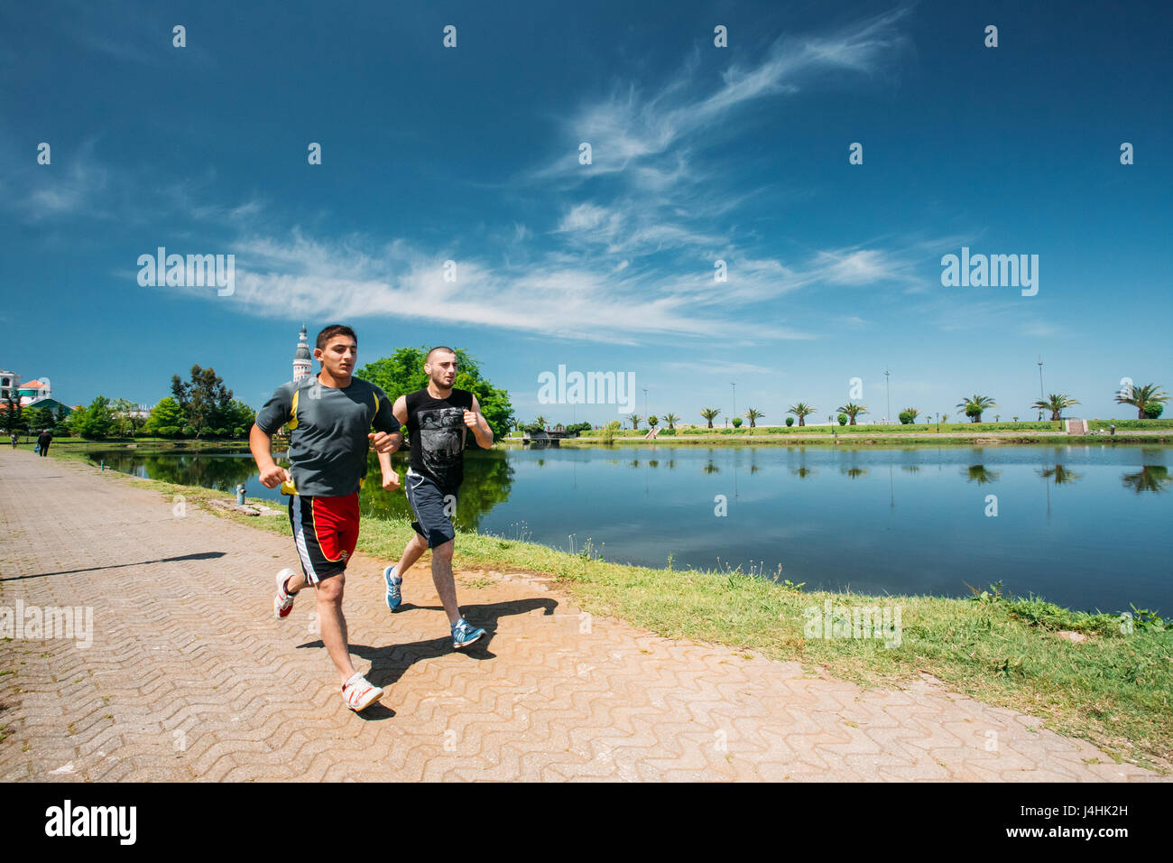 Batumi, Adjara, Georgia - May 25, 2016: Two men athletes jogging on a summer sunny day near Ardagani Lake In Batumi, Adjara, Georgia. Stock Photo