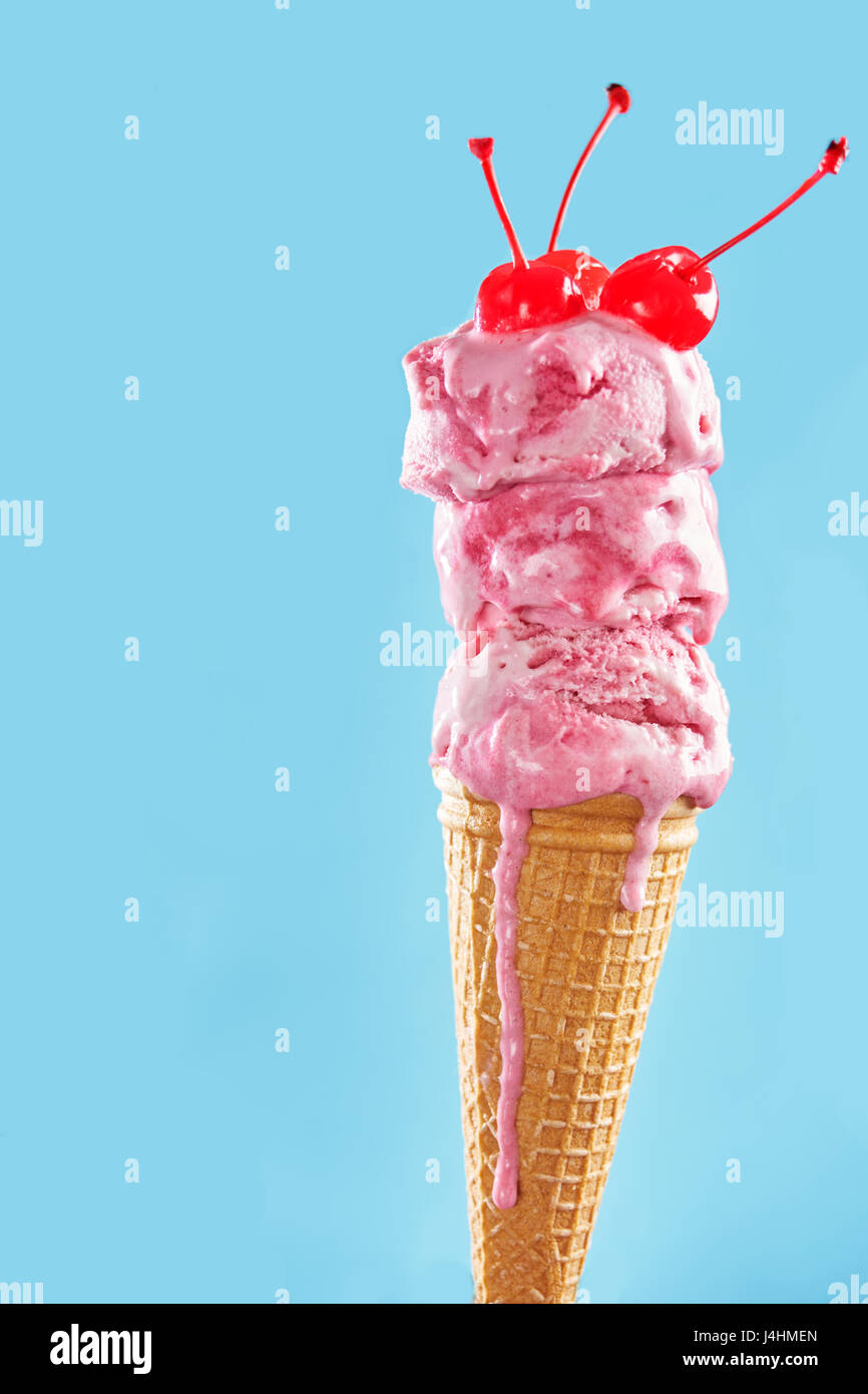 Melting ice cream cone decorated with coctail cherry on blue backround Stock Photo Alamy