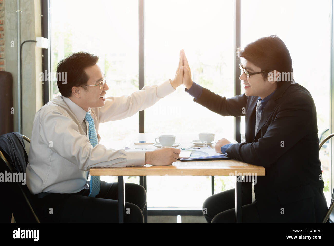 Two Asian happy business man giving high five in cafe. Success and ...