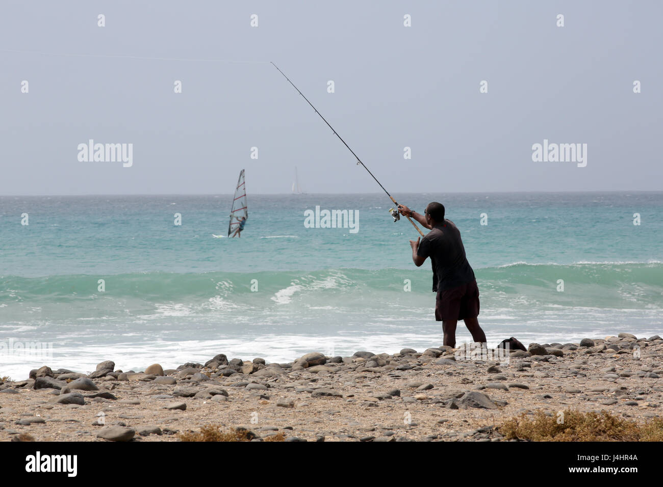 Man fishing off the beach Stock Photo